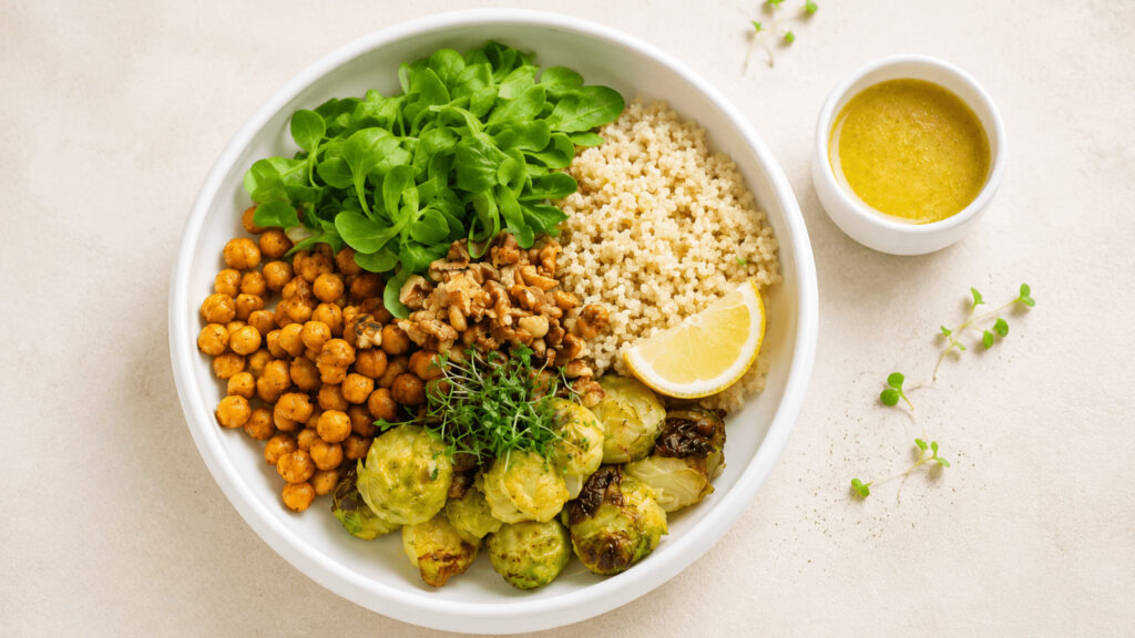 Vegane Rosenkohl-Quinoa-Bowl mit Kichererbsen, Walnüssen und Ahorn-Senf-Dressing, warm angerichtet
