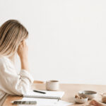 Frau im Alltag, die unter Mental Load steht und Schwierigkeiten hat, sich regelmäßig und gesund zu ernähren. Helle, natürliche Darstellung von Frauengesundheit, Ernährung, Stress und Alltagsbelastung. Symbolische Darstellung dafür, wie Erschöpfung, Decision Fatigue und mentale Last gesunde Ernährung im Alltag beeinflussen.