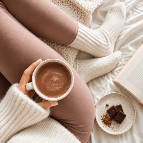 Gemütliche Selbstfürsorge während der Menstruation mit Tee und Decke, Ernährung während der Periode und weiblicher Zyklus im Alltag