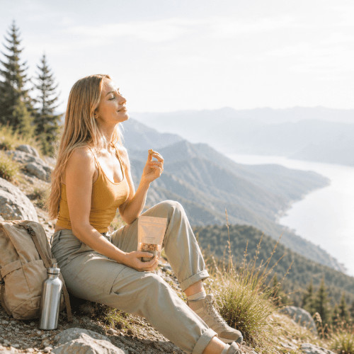 Frau macht beim Wandern eine Pause und isst Nüsse als proteinreichen Snack für langanhaltende Energie in der Ovulationsphase.